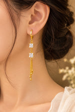 Gold long drop earring worn on ear